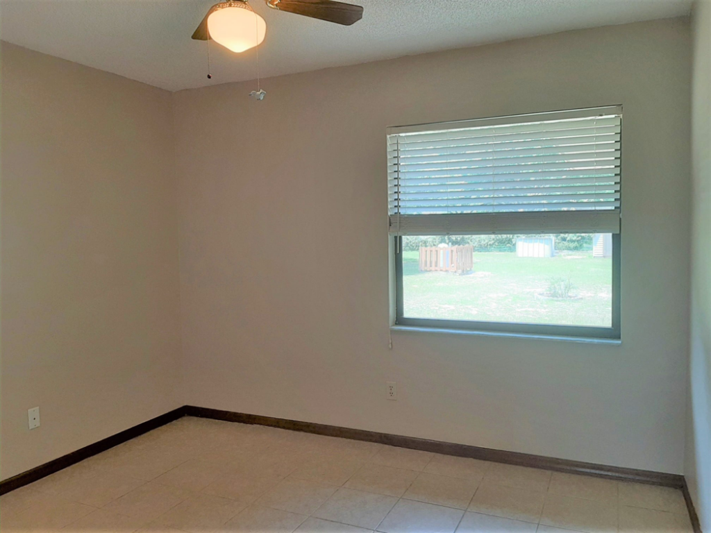 A clean, empty interior room with tiled floor and ceiling fan by Knupper Properties & Knupper Homes in Clermont, FL.