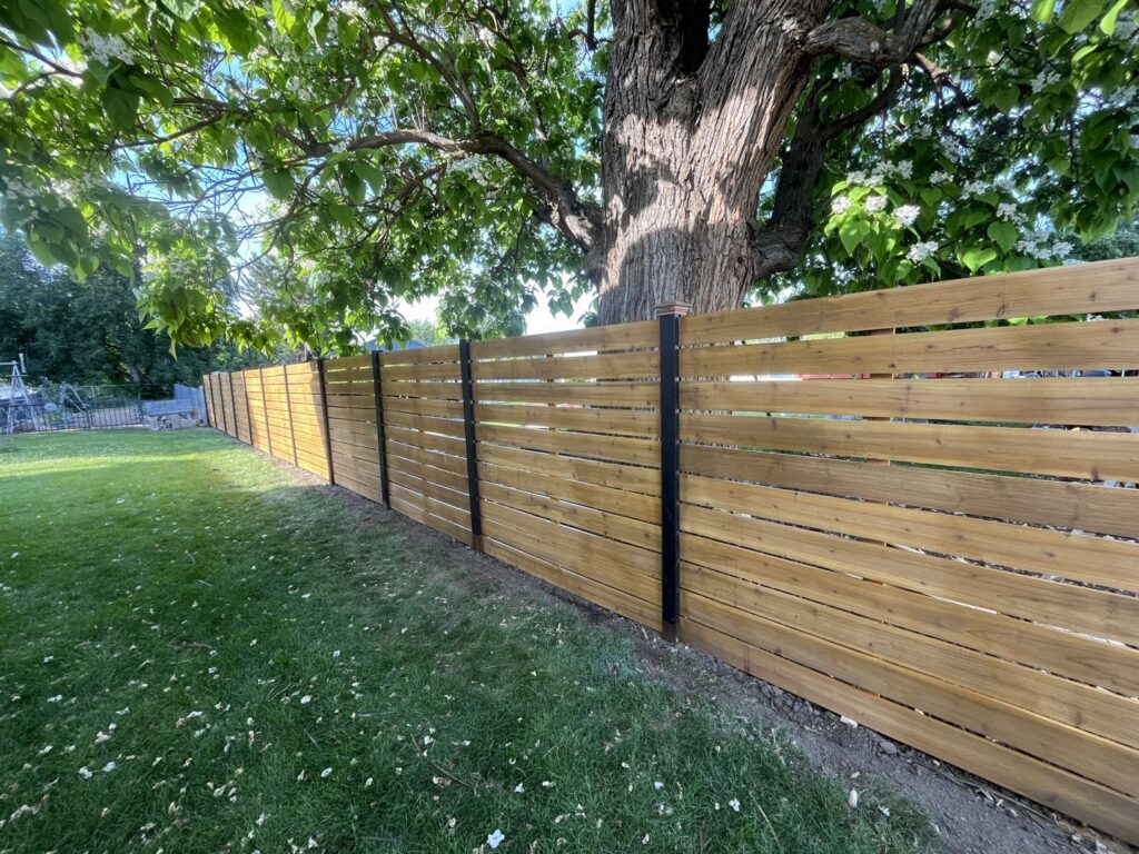 A newly installed horizontal wood fence with black posts in a backyard, completed by Forever Young Handyman Services in Boise, ID.