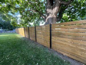 A newly installed horizontal wood fence with black posts in a backyard, completed by Forever Young Handyman Services in Boise, ID.