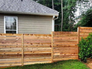 A newly installed horizontal wood fence next to a house, showcasing fence installation by Steven's Deck and Fence Staining Columbus, GA.