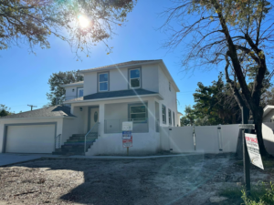 Exterior of a newly built house with a garage and "For Sale" sign by Otero-Cossio Construction in Tampa, FL.