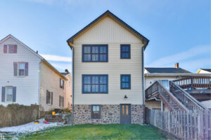 The exterior rear of a newly constructed or renovated house with new siding and stone foundation by Shafer Construction, LLC in Bethlehem, PA.