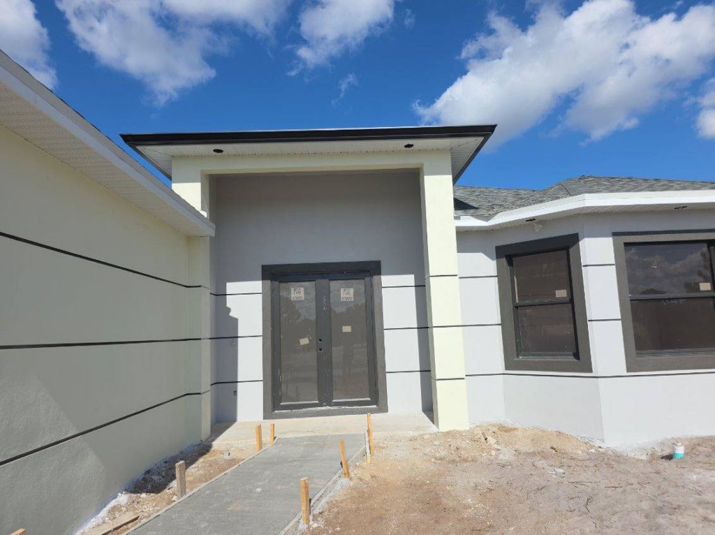 Front entrance of a new house under construction with double doors and a concrete walkway by C.A Tano Construction & Appliances Cgc1531664 in Cape Coral, FL.