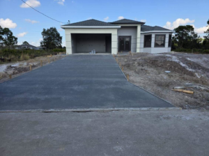 Front view of a new house under construction with a long concrete driveway by C.A Tano Construction & Appliances Cgc1531664 in Cape Coral, FL.