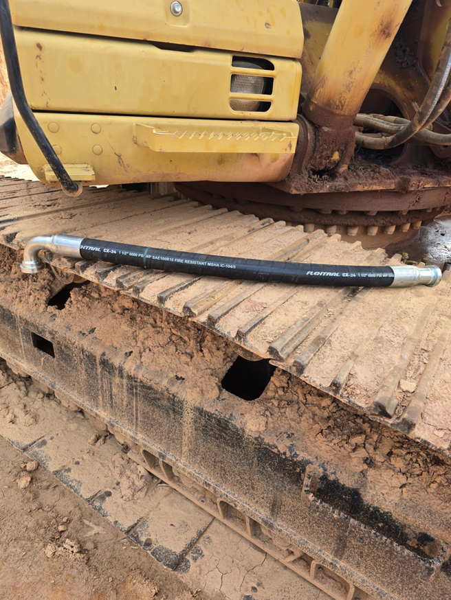 A new hydraulic hose resting on the tracks of heavy equipment, ready for installation by Wise Equipment Services in Rock Hill, SC.