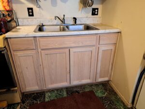 Newly installed wooden kitchen cabinets below a sink, showcasing renovation work by JAMS Property Preservation LLC in Dayton, OH.
