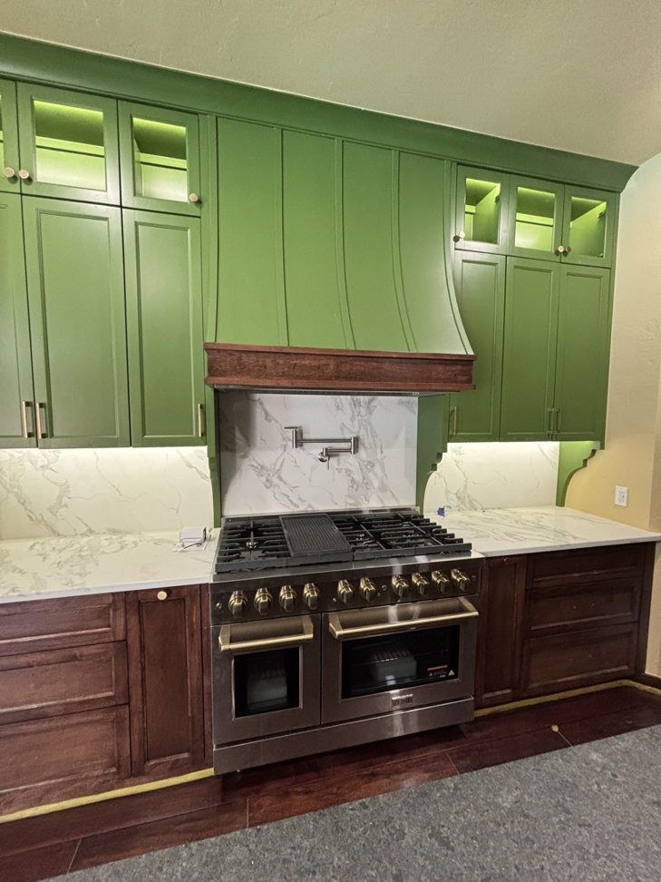 New kitchen installation with green cabinets, marble backsplash, and a large range by New Era Painting & Construction, Jefferson, NC.