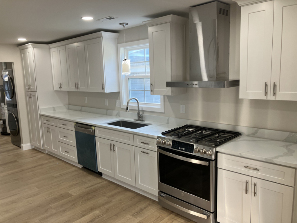 A newly installed kitchen with white cabinets, light countertops, and stainless steel appliances by Precision Home Improvement in Virginia Beach, VA.