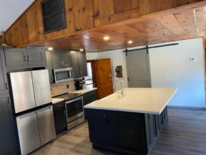 A newly renovated kitchen featuring dark cabinets, stainless steel appliances, and a large island by HMI Contractors in Cincinnati, OH.