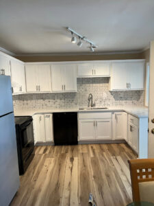 A newly renovated kitchen with white cabinets, a patterned backsplash, and new flooring by Northcross Restoration Inc in Memphis, TN.