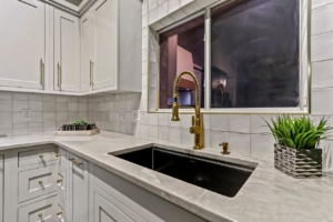 A newly installed kitchen sink with a modern gold faucet and tile backsplash by Innovative Design & Construction in Linwood, KS.