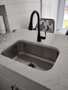 A newly installed modern kitchen sink with a black faucet and white quartz countertop by McCollister Contracting LLC in New Castle, DE.