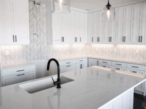 A newly installed kitchen with white cabinets and a herringbone tile backsplash by Brian's Tiles in Duluth, MN.
