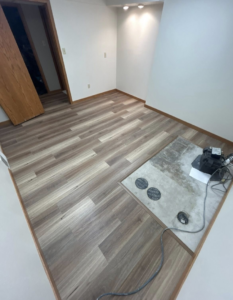 A basement room with newly installed laminate flooring and painted walls by I Need a Guy Handyman Services LLC in Moorhead, MN