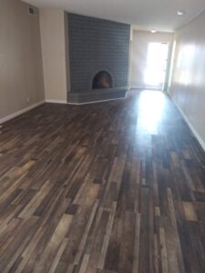 A renovated living space featuring new laminate flooring and a painted brick fireplace by Red Gator Maintenance in Fresno, CA.