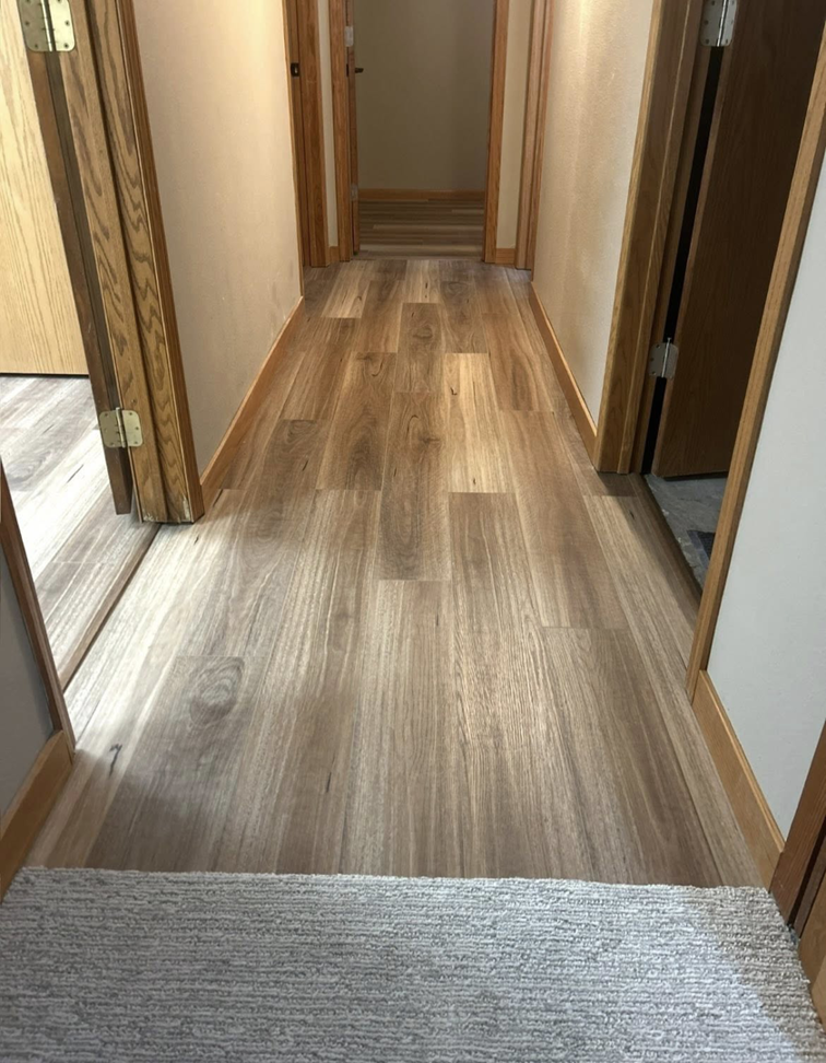A newly installed laminate flooring in a hallway by I Need a Guy Handyman Services LLC in Moorhead, MN