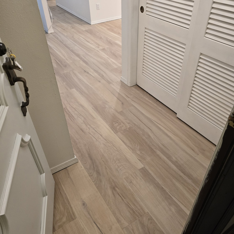Newly installed light wood-look laminate flooring in a hallway by L.A. Floors in Madison, WI.