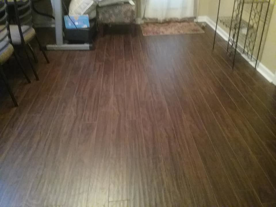 Newly installed dark laminate flooring in a room, a service provided by The House Doctor in Hopkinsville, KY.