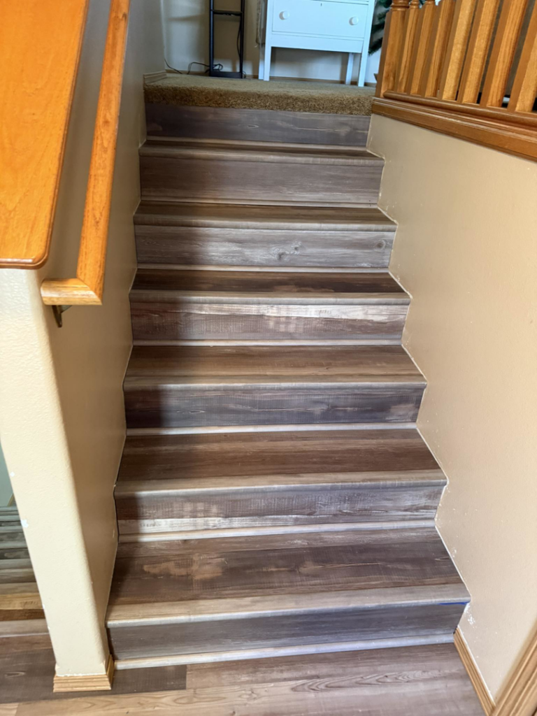 Newly installed laminate flooring on a staircase, showcasing quality work by Watertown Handyman in Watertown, SD.