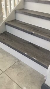 Newly installed laminate wood-look stair treads with white risers by SD Masters in Miami, FL.