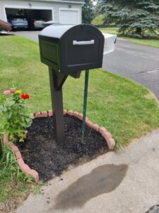 A newly installed black mailbox with decorative landscaping, completed by Pink Rose Home Service in Rochester, NY.