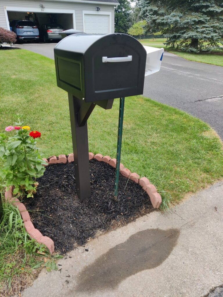 A newly installed black mailbox with decorative landscaping, completed by Pink Rose Home Service in Rochester, NY.