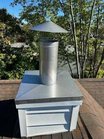 A newly installed metal chimney cap and flue on a roof by Universal Builders LLC in New Haven, CT.