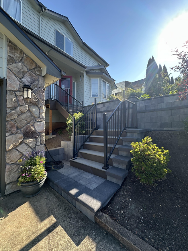 Newly built outdoor stairs with black railings and a stone retaining wall by Rosas Construction and Renovation in Dallas, TX.