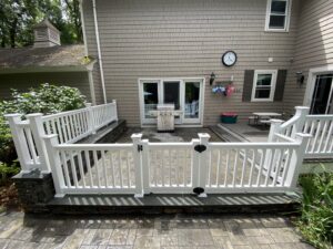A newly installed patio with white fencing and stone veneer work by Eagle Exteriors in Cumberland, RI.