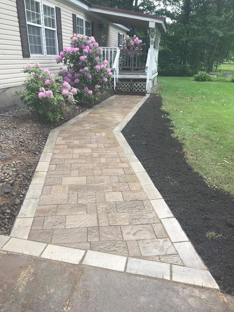 A newly installed paver walkway leading to a house entrance by Carl Gardner Contracting in Syracuse, NY.