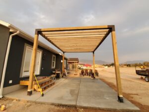 Newly constructed wooden pergola frame over a concrete patio by Jonny Handyman Services in Roy, UT.