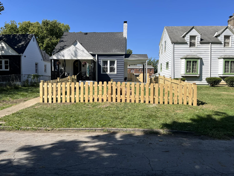 A newly installed wooden picket fence in front of a house, completed by JB Recovery in Columbus, OH.