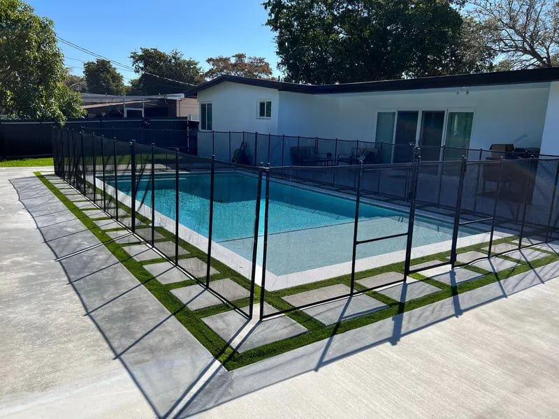 A newly installed swimming pool with a black safety fence, completed by BAFCO POOLS in Hialeah, FL.