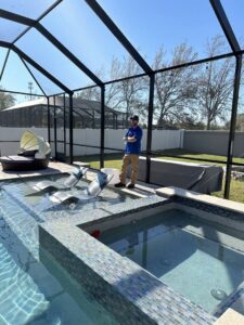 A newly installed pool and spa with modern tiling and a screen enclosure by JJB Pools & Spas in Tampa, FL.