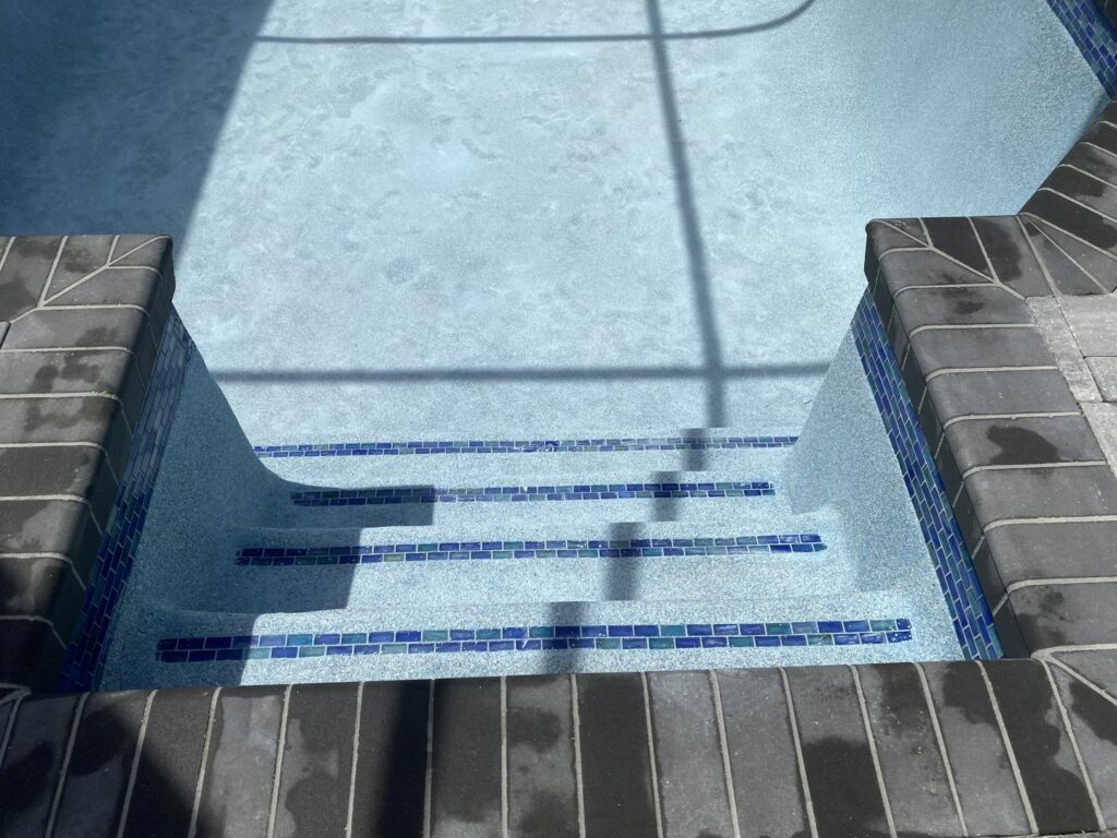 Close-up of newly tiled and plastered pool steps, showcasing quality craftsmanship by JJB Pools & Spas in Tampa, FL.