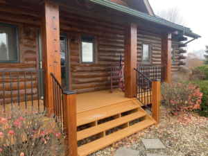 A newly installed porch deck and black metal railings on a log cabin home by Building Arts by Jimmy Z in Cassville, WI.