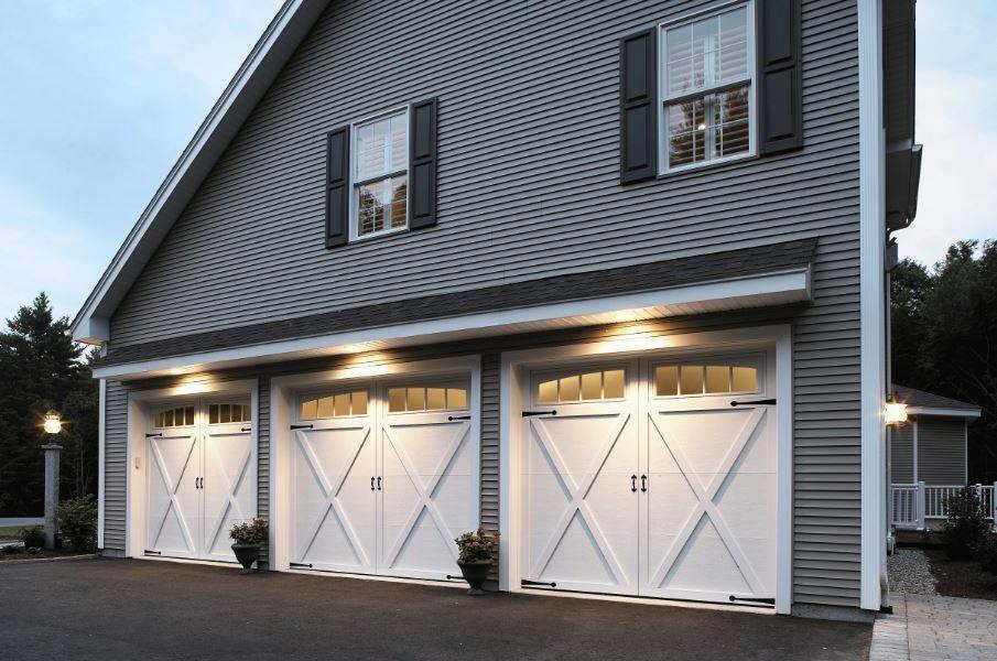 Newly installed white residential garage doors on a grey house by Overhead Door Company of Columbus in Columbus, GA.