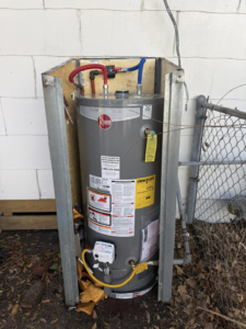 A newly installed Rheem outdoor water heater with plumbing connections by High Tide Home Remodeling in Charleston, SC.