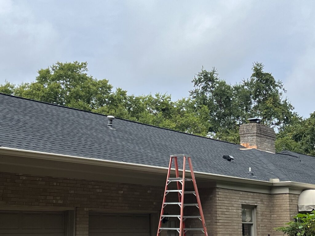 A newly installed dark shingle roof with a ladder leaning against the house by Music City Exteriors in Nashville, TN