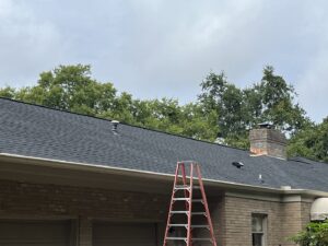 A newly installed dark shingle roof with a ladder leaning against the house by Music City Exteriors in Nashville, TN