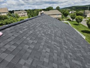Close-up of a new shingle roof installation with a worker on the ridge by Moonshot Roofing in Columbia, PA.