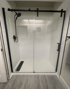 A newly installed shower enclosure with black framing and white subway tiles by Peraza Handyman Services Llc in Bakersfield, CA.