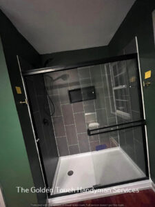 A newly installed shower enclosure with dark tiles and green walls by The Golden Touch handyman services in Huntington, WV.