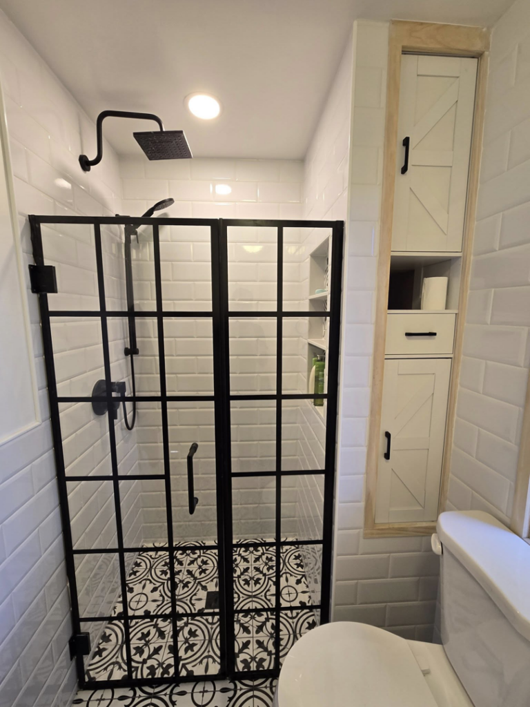 A modern new shower installation with a black grid door and patterned tile floor by All In Remodeling Services LLC in Arvada, CO.