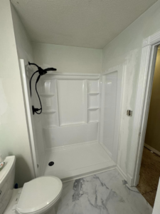 A newly installed shower unit and toilet in a bathroom, completed by Tackett's Pro Trade Services in Berea, KY.