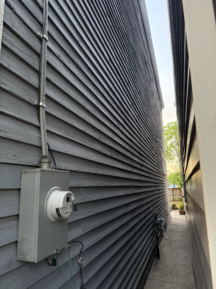 Newly installed dark gray siding and an electrical meter on the side of a house by Isac's General Services LLC in Henrico, VA