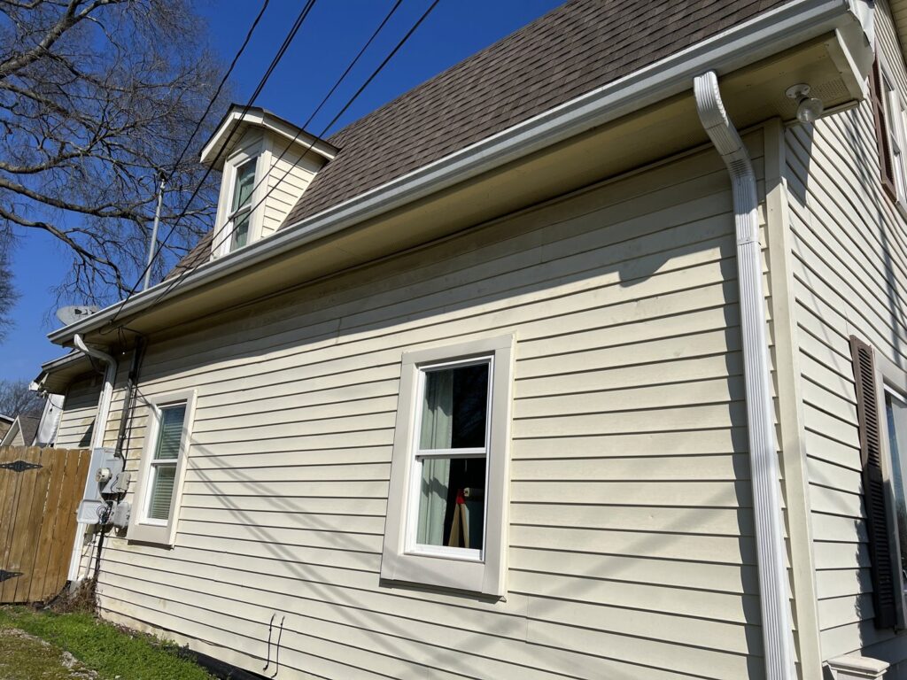 The side of a house featuring newly installed light siding and white gutters by Music City Exteriors in Nashville, TN