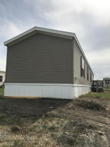 New grey siding and white skirting installed on a manufactured home by Devotion Construction LLC in Pierre, SD.