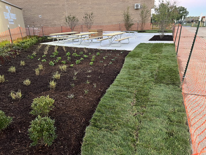Newly installed sod, planted garden beds, and picnic tables on a concrete patio by NARDI Construction, Inc. in Frederick, MD.