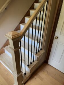A newly installed wooden staircase with modern black metal balusters by Triple M Handyman in Portsmouth, NH.